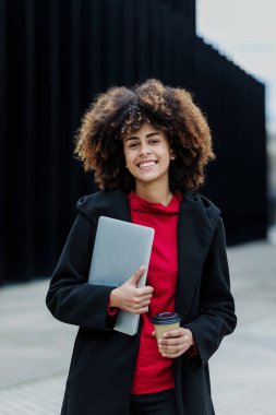 Latin Amerika 'da dizüstü bilgisayar tutan genç Afrikalı Amerikalı iş kadını, İspanyol finans ve Karayipliler 