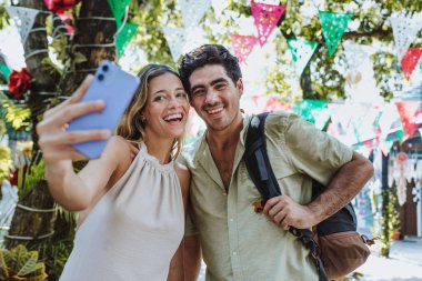 hispanic young couple taking photo selfie on vacations or holidays in Mexico Latin America, Caribbean and tropical destination  clipart