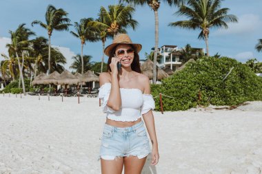 Latin kadın cep telefonu kullanıyor ve Meksika 'daki Karayip Sahili' nde konuşuyor. Latin kökenli, tropikal kökenli bir kadın.