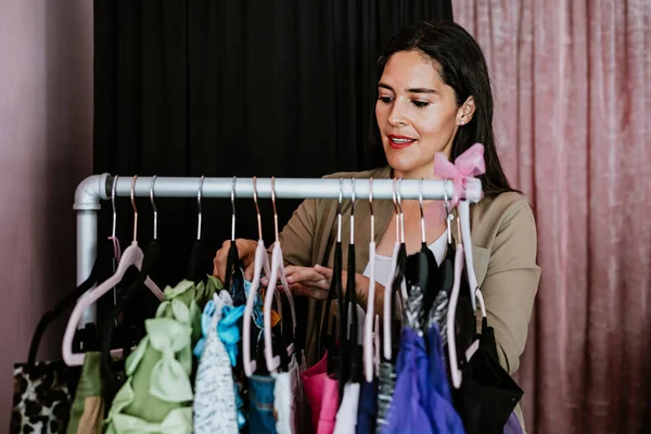 latin woman customer shopping in Clothing Store choosing and trying on Clothes in Mexico Latin America, hispanic small business fashion industry