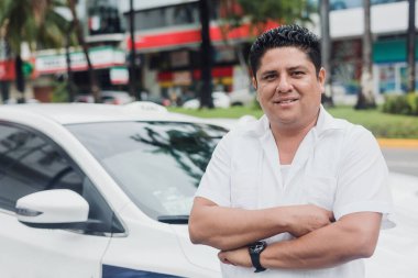 Latin Amerika 'da Mexico' da şehir sokağında arka planda arabası olan Latin bir taksi şoförü.
