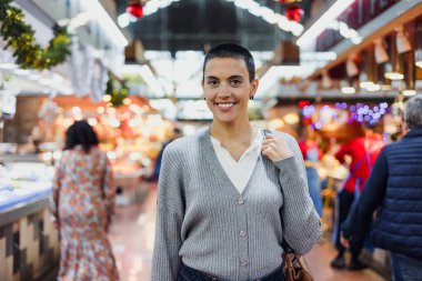 Dazlak ya da kısa saçlı İspanyol genç kadın geleneksel markette ya da markette sebze alışverişi yapıyor. 