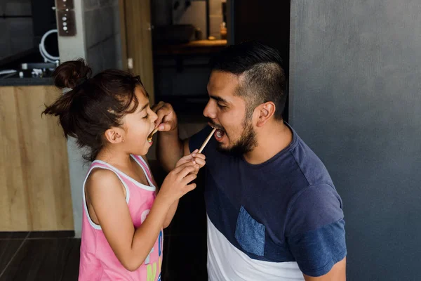 latin young single father teaching to his daughter how to brush her teeth at home in Mexico Latin America, hispanic family