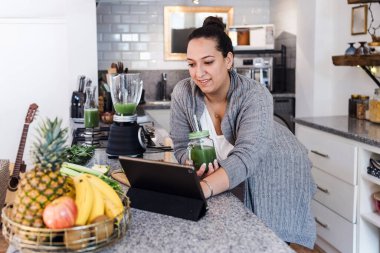Latin Amerika 'da çatı katında yeşil meyve suyu içen Latin bir kadın, evde Meksikalı bir kadın.