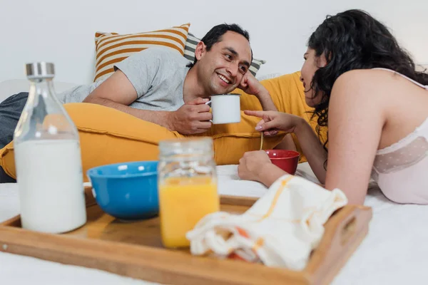 Latin couple having breakfast in bed at home in Mexico Latin America, hispanic people having fun
