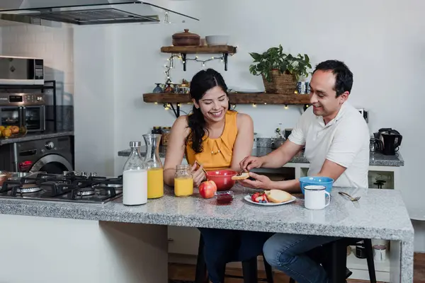 latin couple having breakfast with juice and fruits at kitchen in home in Mexico Latin America, hispanic people eating