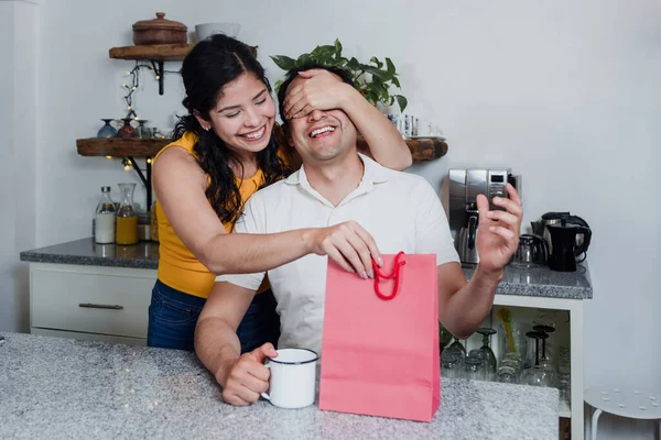 Latin married couple man and woman give a gift for holiday at home in Mexico Latin America, hispanic couple in celebration