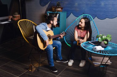 Romantik bir buluşmada gitar çalan genç Latin bir çift, Meksika 'da gece evde şarkı söyleyen kız arkadaş ve erkek arkadaş, Latin Amerikalılar.