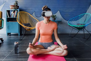 Latin kadın, Meksika Latin Amerika 'da minder üzerinde meditasyon yaparken ve evde yoga yaparken sanal gerçeklik gözlüğü kullanıyor, İspanyol kadın refahı