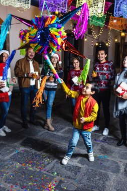 Hispanic family breaking a pinata at traditional mexican posada celebration for Christmas in Mexico Latin America clipart