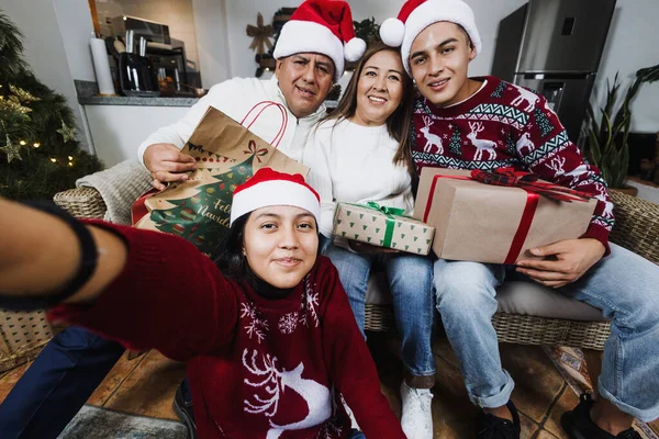 Latin family taking self portrait with mobile phone during Christmas eve at home in Mexico Latin America. hispanic people mother, father with teen son and daughter
