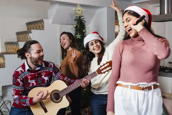 group of Latin friends singing in karaoke party celebrating christmas eve at home in Mexico Latin America, hispanic people in holidays