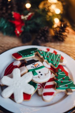 Çarşaflı Noel kurabiyeleri ya da kırsal masada altın ışıklı tabaklar. Geleneksel kardan adam, ağaç, yıldız kurabiyeleri ve Noel Baba şapkası pişirmek..