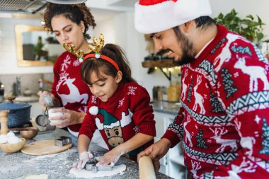 Latin aile, anne, baba ve kız Meksika 'da evde Noel kurabiyesi pişiriyorlar.