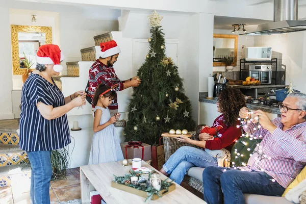 Latin Family parents and daughter with grandparents decorating christmas tree at home in mexico Latin America in holidays