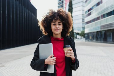 Latin Amerika 'da dizüstü bilgisayar kullanan genç Afrikalı Amerikalı iş kadını, afro saçlı ve gökdelen geçmişi olan İspanyol ve Karayipliler.