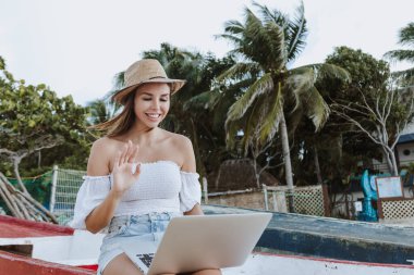 Latin woman using laptop or computer at Caribbean Beach working as digital nomad in Mexico Latin America, hispanic female clipart