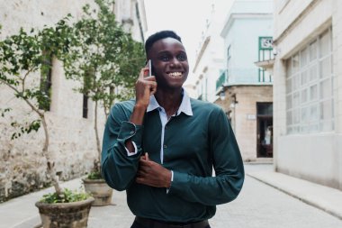 Genç Afrikalı Amerikalı cep telefonuyla konuşuyor, Latin Amerika 'da genç Karayipli siyahlar mesaj yolluyor.