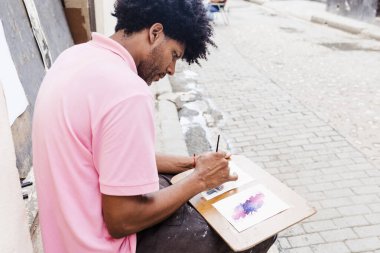 Latin Amerika 'da boyaları ve fırçaları kullanarak sokak ressamlığı yapan Afro-Amerikan erkek ressam ya da ressam.