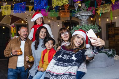 Geleneksel partiyi kutlayan Meksikalı aile Noel arifesi ve Meksika Latin Amerika 'da tatiller için posadalarda cep telefonlarıyla selfie çekiyor.