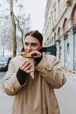 Paris sokaklarında leziz krepler yiyen Fransız kadın, Avrupa 'da geleneksel krepleri tutan eller.