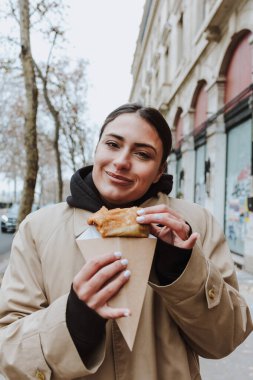 Paris sokaklarında leziz krepler yiyen Fransız kadın, Avrupa 'da geleneksel krepleri tutan eller.