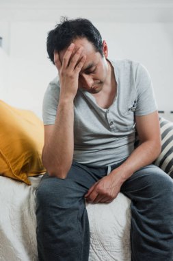 Yalnız Latin bir adam kendini depresyonda ve stresli hissediyor. Meksika 'da yatak odasında baş başa oturuyor. Latin Amerika' da depresyon ve anksiyete bozukluğu olan İspanyol insanlar.