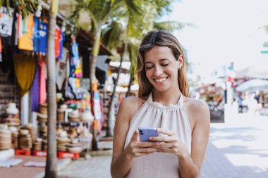 Latin Amerika, Karayipler ve tropikal tatil için Meksika 'da telefon kullanan İspanyol genç kadın.