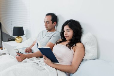 Latin çift kitap okuyor ve daha önce Meksika 'da Latin Amerika' da evde uyumak için dizüstü bilgisayar kullanıyordu.