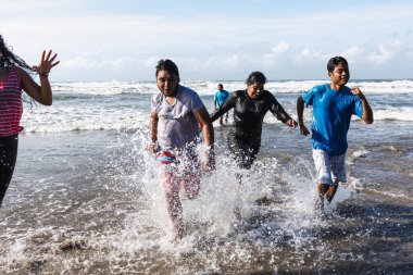 Acapulco Meksika 'nın Pasifik Okyanusu' ndaki plajda atlayıp koşan mutlu Latin arkadaşlar Latin Amerika 'da, İspanyol gençler kadınlar ve erkekler eğleniyor. 