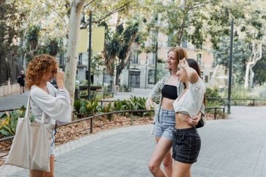 İspanyol ve çok ırklı kızlar şehrin caddesinde klasik kamerayla fotoğraf çekiyorlar. Bir grup çok ırklı kadın arkadaş.
