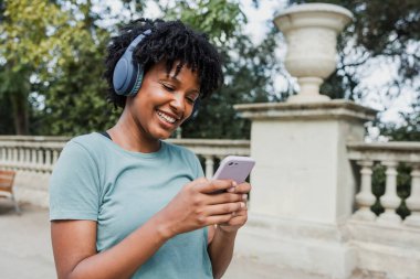 Avrupa 'nın İspanya şehrinde kulaklık ve cep telefonu kullanan genç siyahi kadın.