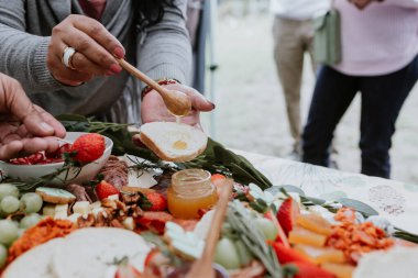 Eller ve açık büfe tahtası, ahşap masada şarap ve peynir.