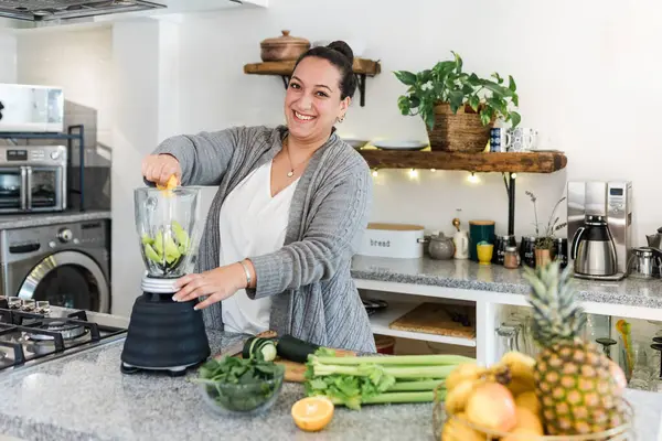 Latin kadın aşırı kilolu detoks hazırlıyor ya da Meksika Latin Amerika 'da mutfakta yeşil meyve suyu, Meksikalı kadın artı diyet için sebze hazırlıyor.