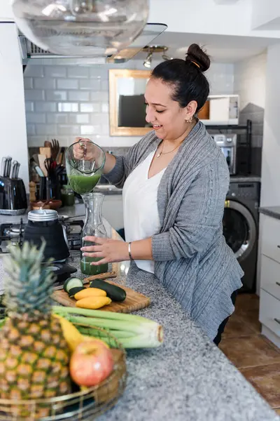 Latin kadın aşırı kilolu detoks hazırlıyor ya da Meksika Latin Amerika 'da mutfakta yeşil meyve suyu, Meksikalı kadın artı diyet için sebze hazırlıyor.