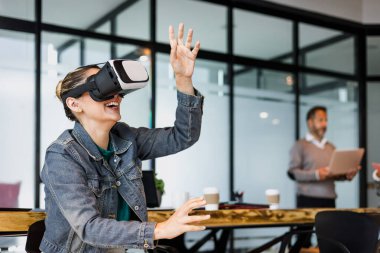 Latin Amerika 'daki ofiste sanal gerçeklik gözlüğü kullanan genç İspanyol kadın, vr teknolojisinde birlikte çalışan Latin insanlar ve takım çalışması 