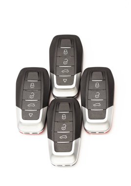 Arabanın anahtarları beyaz arka planda farklı pozlarda duruyor. Siyah ve kırmızı alarm tuşları beyaz arka planda yer almaktadır.