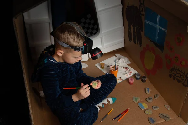 Ukraynalı bir çocuk karton bir evde ışıksız oturuyor ve resim çiziyor. Nazilerin bombardımanından sonra Ukraynalı bir çocuk karanlık bir odada fenerle resim çiziyor. Ukrayna 'da Savaş