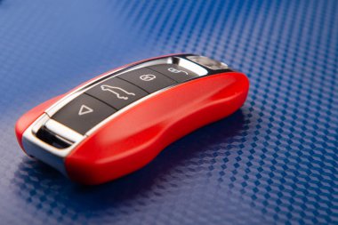 The key to the sports car is red, lies on a blue background. clipart