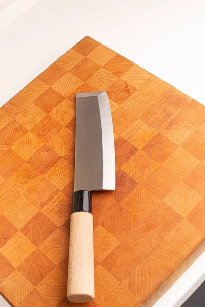 Tahta bir tahtanın üzerinde Japon Nakiri mutfak bıçağı ve ahşap sapı var..