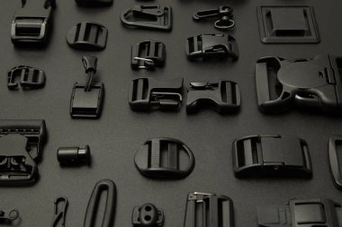 Siyah arka planda siyah kıyafetler için aksesuarlar. Kolaj (hızlı, lastik bantlar, düğmeler, kıyafetler için kilitler)