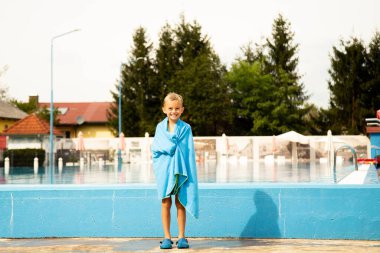 Avrupa görünümlü yedi yaşında bir çocuk havuz kenarında poz veriyor ve surat yapıyor..