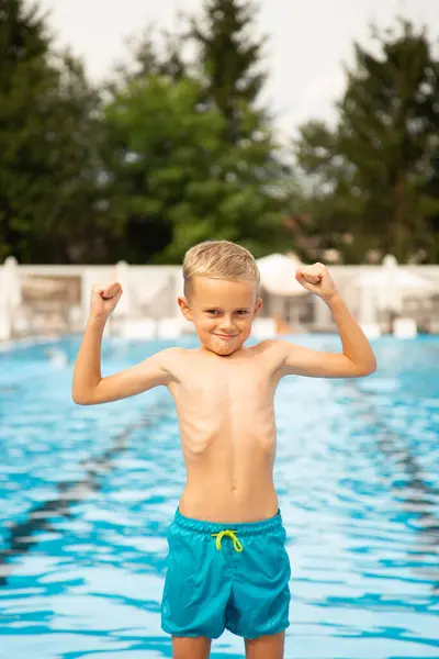 Avrupa görünümlü yedi yaşında bir çocuk havuz kenarında poz veriyor ve surat yapıyor..