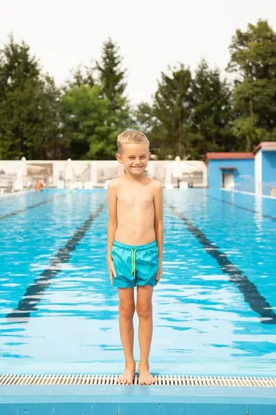 Avrupa görünümlü yedi yaşında bir çocuk havuz kenarında poz veriyor ve surat yapıyor..