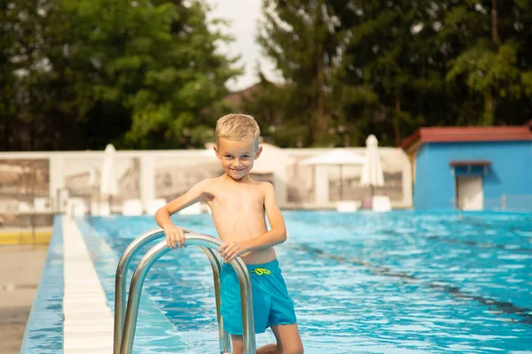 Avrupa görünümlü yedi yaşında bir çocuk havuz kenarında poz veriyor ve surat yapıyor..