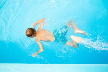 Avrupa görünümlü yedi yaşındaki bir çocuk havuza atlıyor.