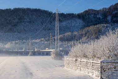 Kış manzarası, dağlar ve ağaçlar karda, güneş ışıl ışıl parlıyor..