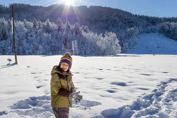 Mutlu gülümseyen kız kışın karla oynuyor.