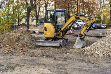 İşte küçük bir buldozer. Turuncu kazıcı yolda. Şehirdeki inşaat işleri..