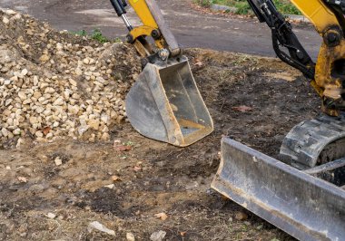 İşte küçük bir buldozer. Turuncu kazıcı yolda. Şehirdeki inşaat işleri..